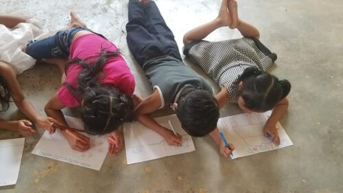 Niños de Kalimananga dibujando tumbados en el suelo durante una actividad